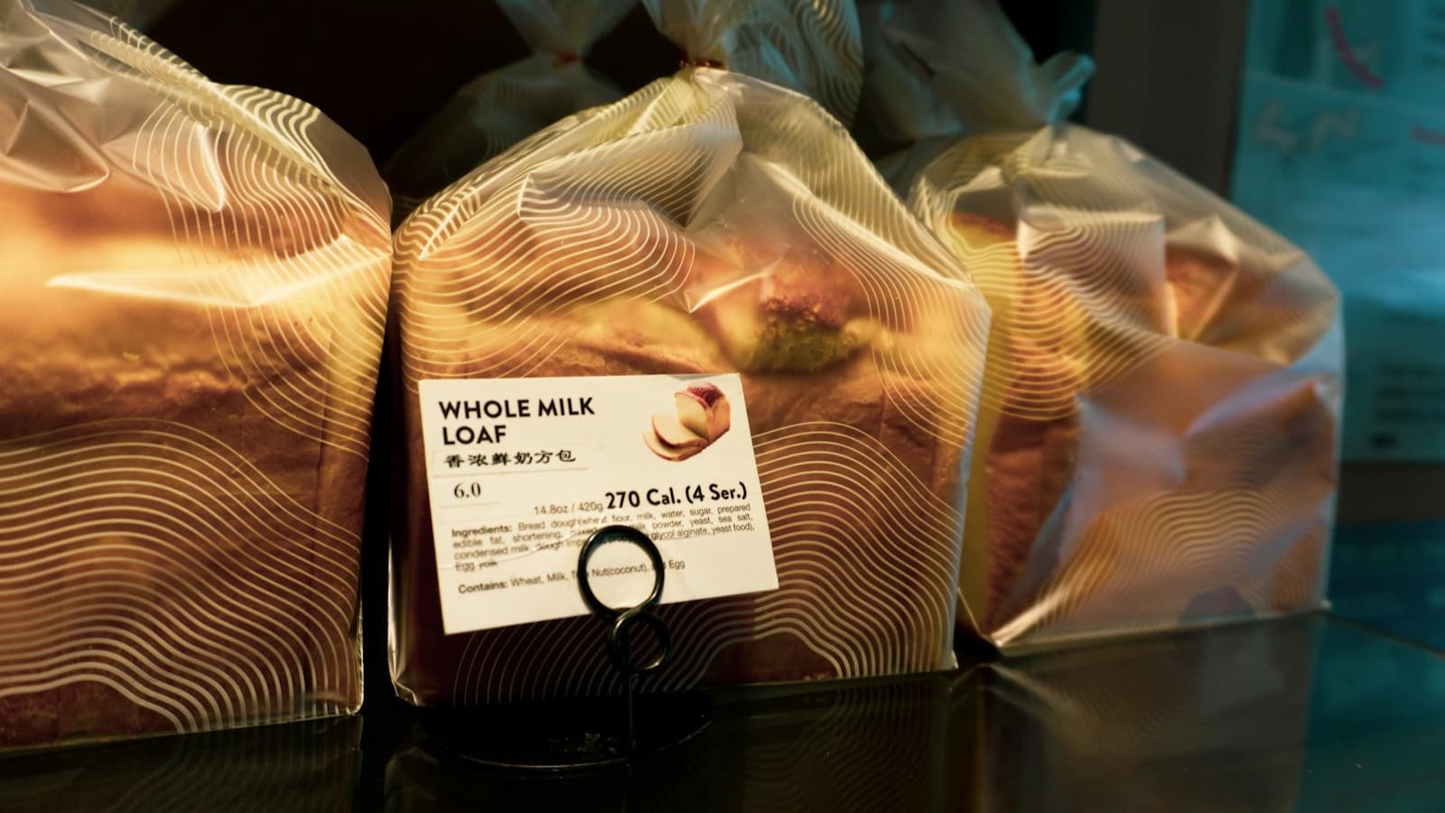 Milk loaves in clear bags on a shelf, with a label in front showing the name, weight, ingredient list and allergens