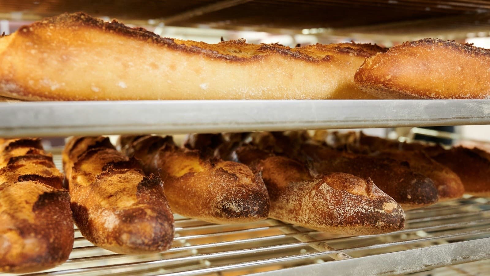 Freshly baked baguettes and loaves cooling on the steel racks of a bakery trolley