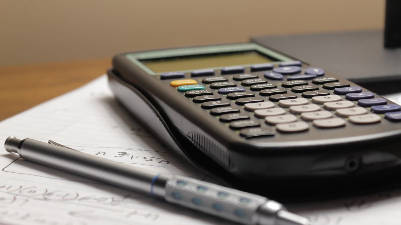 A pastry chef calculating prices with a notebook, a calculator and coffee on the table